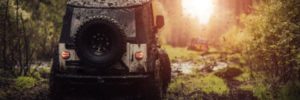 A Jeep drives through a muddy terrain